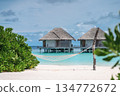 Panoramic view of luxury water villas and tropical beach framed by palm leaves, Maldives 134772672