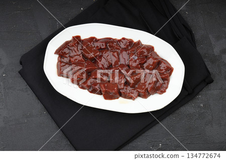 Cut raw beef liver with onions, spices, chili peppers and dill on wooden table, flat lay Cut raw beef liver with onions, spices, chili peppers and dill on wooden table, flat lay 134772674