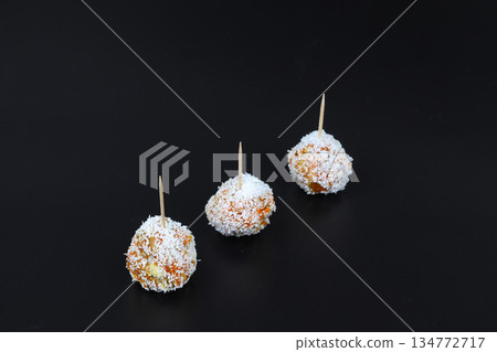 Beautiful sweets with coconut on a black plate on a black background close-up Beautiful sweets with coconut on a black plate on a black background close-up 134772717