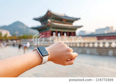 Individual checking smartwatch while standing near traditional architecture, highlighting the contrast between modern technology and historical surroundings with copy space 134772809