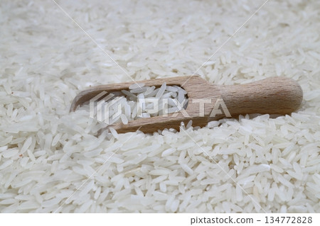 Raw white rice on wooden background. Long uncooked rice in wooden plate. Natural organic food. Traditional Asian cereal culture. 134772828