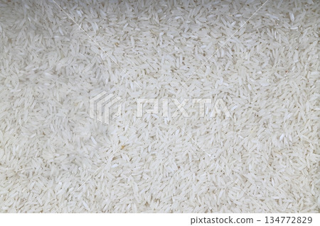 Raw white rice on wooden background. Long uncooked rice in wooden plate. Natural organic food. Traditional Asian cereal culture. Raw white rice on wooden background. Long uncooked rice in wooden plate. Natural organic food. Traditional Asian cereal culture. 134772829