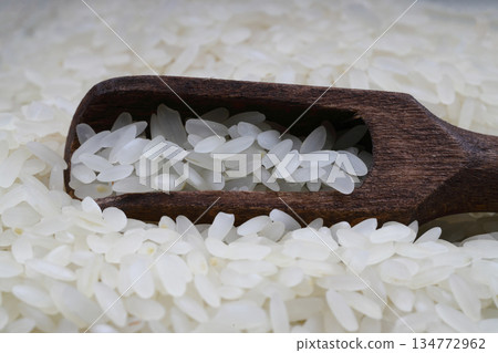 Raw white rice on black background. Long uncooked rice in wooden plate. Natural organic food. Traditional Asian cereal culture. 134772962