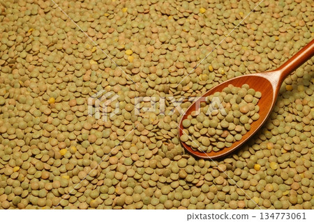 Green lentils scattered close-up with a spoon. 134773061