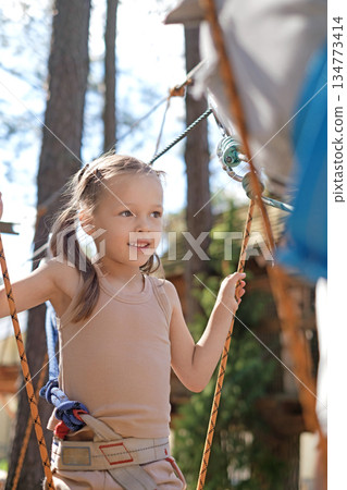 A happy little girl follows her father along the cable car. Outdoor amusement park in the forest 134773414