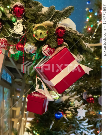 A Christmas tree with a red box hanging from it. The box is decorated with a ribbon and has a bow on top. A Christmas tree with a red box hanging from it. The box is decorated with a ribbon and has a bow on top. 134773697