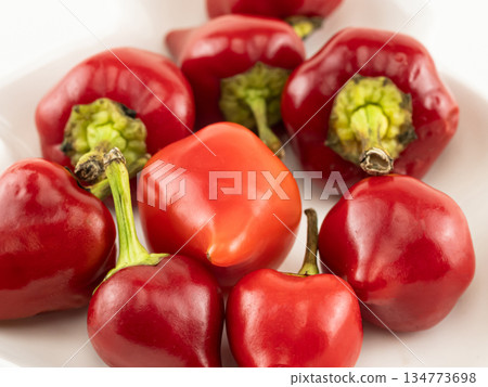 A plate of red peppers with one of them shaped like a heart A plate of red peppers with one of them shaped like a heart 134773698
