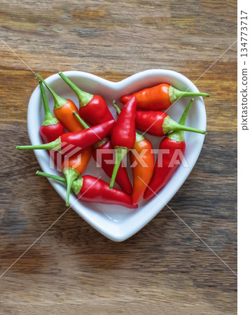 plate full of hot red peppers on wooden background with copy space 134773717