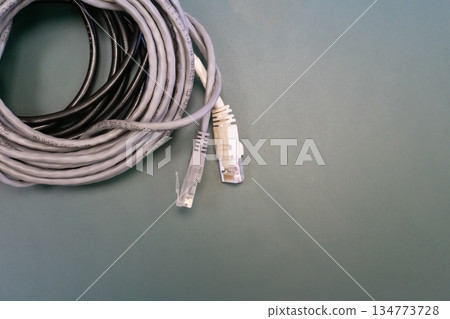 A white and gray cable rj45 is laying on a green surface 134773728