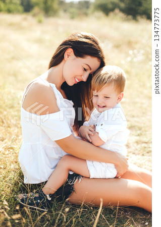 Mother enjoying outdoor moments with her sons in a sunlit field, capturing everyday family joy and bonding Mother enjoying outdoor moments with her sons in a sunlit field, capturing everyday family joy and bonding 134773775