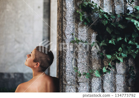 Person looking up near stone wall with ivy 134773792