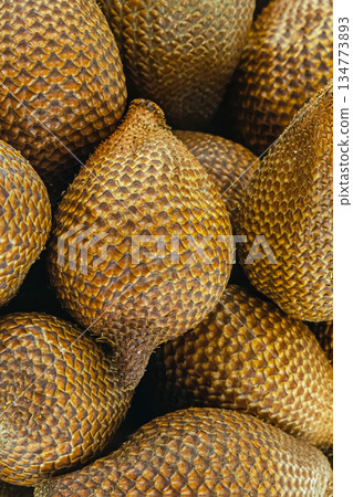 tropical herring fruit, snake fruit lies in a wooden bowl stands on a white background tropical herring fruit, snake fruit lies in a wooden bowl stands on a white background 134773893