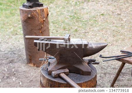 A black iron anvil with a hammer and other tools on top of it. 134773918
