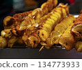 Delicious potato skewers topped with spices served at a street food market during evening hours 134773933