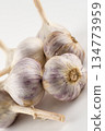 large and mature three heads of white garlic stand on a white background close-up 134773959