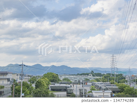 郊區景色，背景是軍事基地、雲朵和山巒。 134774289