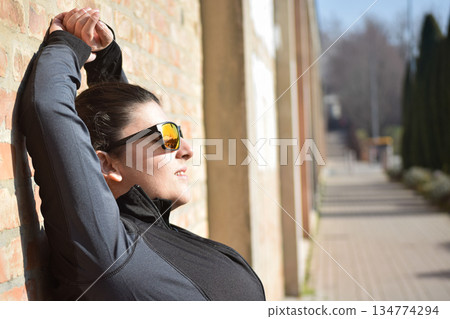 Woman with visual disabilities exercising in the park and stretching 134774294