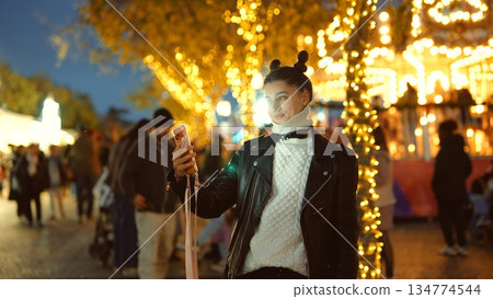 Relaxed woman explores vibrant illuminated fairground streets Relaxed woman explores vibrant illuminated fairground streets 134774544