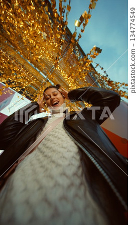Cheerful lady in warm coat surrounded by festive lighting Cheerful lady in warm coat surrounded by festive lighting 134774549