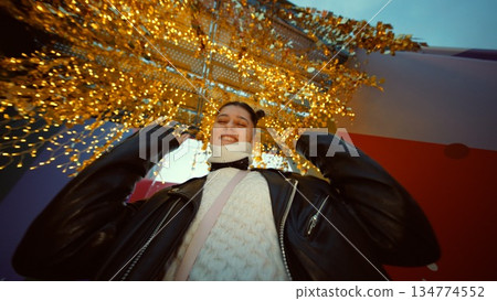 Cheerful woman enjoying street food under festive lights Cheerful woman enjoying street food under festive lights 134774552