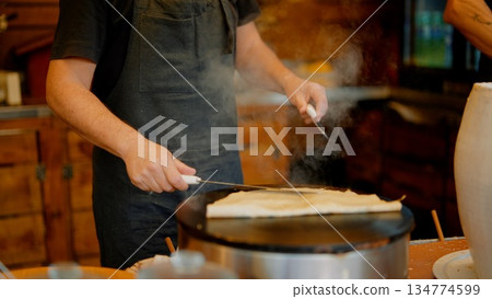 Using steady hands and spreader to shape batter into even circle Using steady hands and spreader to shape batter into even circle 134774599