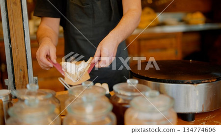 Busy street food vendor preparing warm crepes for takeaway Busy street food vendor preparing warm crepes for takeaway 134774606