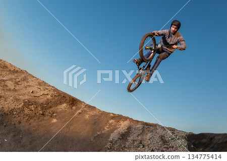 BMX Bike jump over a dirt trail BMX Bike jump over a dirt trail 134775414