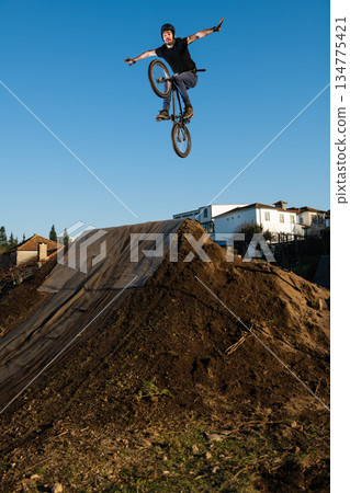 BMX Bike jump over a dirt trail 134775421
