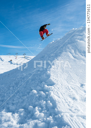 Snowboarder jumping against blue sky Snowboarder jumping against blue sky 134775611