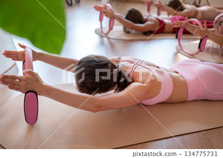 Exercises with pilates ring. Woman doing aerobics workout at pilates studio with panoramic windows. 134775731
