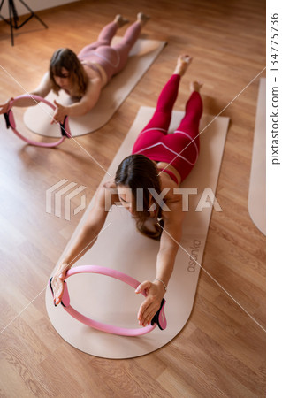 Exercises with pilates ring. Woman doing aerobics workout at pilates studio with panoramic windows. 134775736