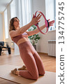 Woman perform synchronized shoulder conditioning with pilates rings overhead in bright studio 134775745