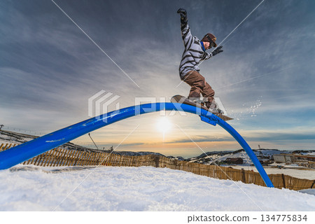 Snowboarder sliding on a rail 134775834