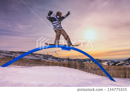 Snowboarder sliding on a rail Snowboarder sliding on a rail 134775835