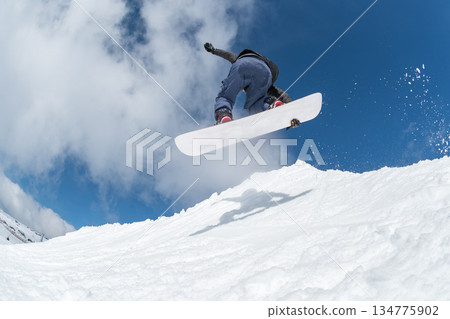 Snowboarder jumping against blue sky 134775902