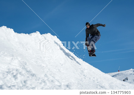 Snowboarder jumping against blue sky 134775903