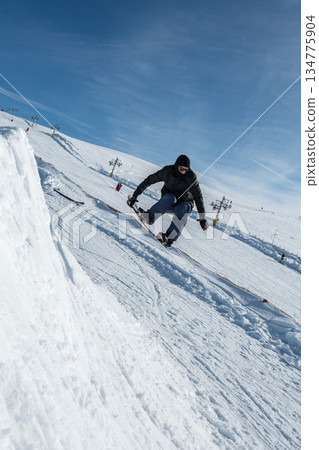 Snowboarder jumping against blue sky 134775904