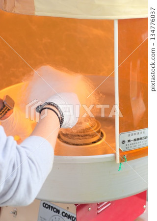 Cotton candy being made at a festival stall - A look at the process of making cotton candy as it rotates in a cooking machine 134776037