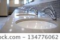 Row of modern stainless steel faucets and sinks in public restroom 134776062