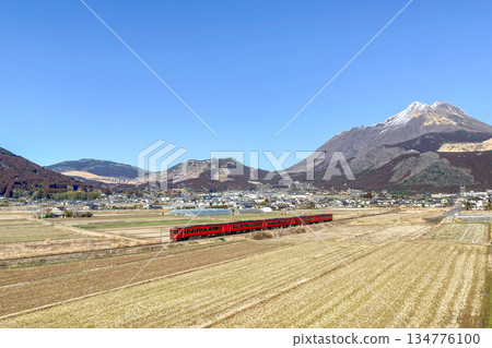 A red train running through Mt. Yufu and the Yufuin Basin in winter 134776100