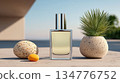 Elegant perfume bottle placed beside decorative stones and a green plant against a serene outdoor background 134776752
