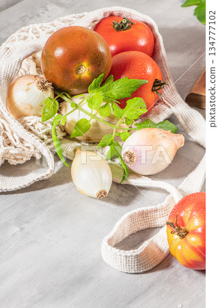 Large variety of tomatoes on rustic kitchen counter. Preparation of tomato sauce with onions and basil Large variety of tomatoes on rustic kitchen counter. Preparation of tomato sauce with onions and basil 134777102