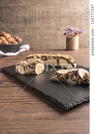 Fresh banana with melted chocolate and nuts coverage Fresh banana with melted chocolate and nuts coverage 134777247
