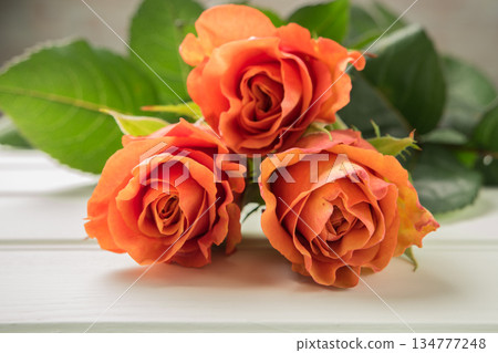 A bouquet of orange roses on wooden table. Copy space 134777248