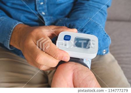 Person measuring blood pressure at home for health monitoring Person measuring blood pressure at home for health monitoring 134777279