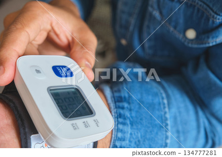 Person checking blood pressure using a digital tonometer 134777281