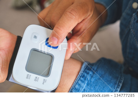 Person checking blood pressure using wrist monitor device Person checking blood pressure using wrist monitor device 134777285