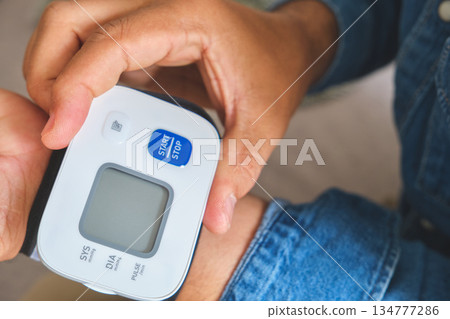 Person checking blood pressure using wrist monitor 134777286