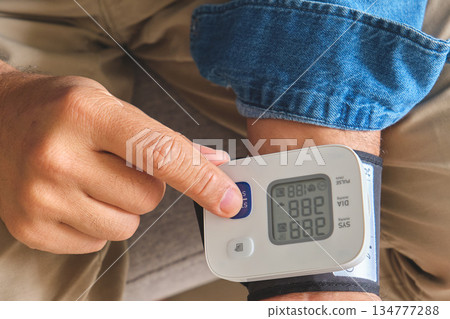 Man checking blood pressure on wrist monitor for health Man checking blood pressure on wrist monitor for health 134777288