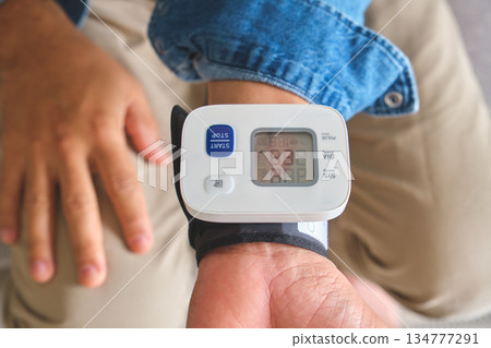Person checking blood pressure with wrist monitor at home Person checking blood pressure with wrist monitor at home 134777291